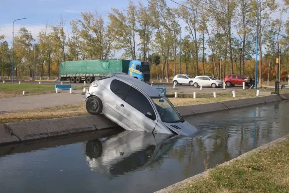 El coche tiene gran parte del frente bajo el agua y las ruedas traseras sobre el borde del canal. Foto. Tania Domenucucci (ANRoca)